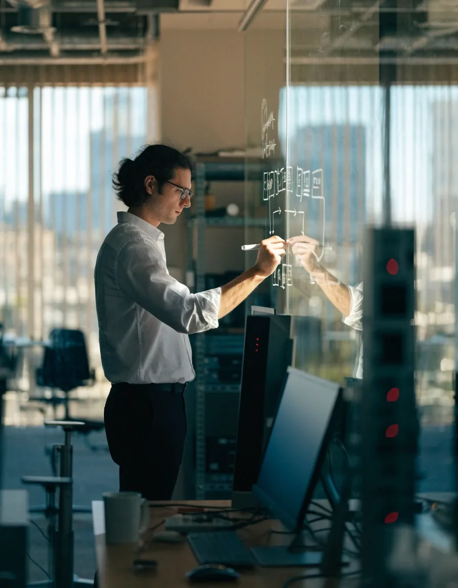 Two Sidebench engineers discussing a system architecture diagram on a whiteboard